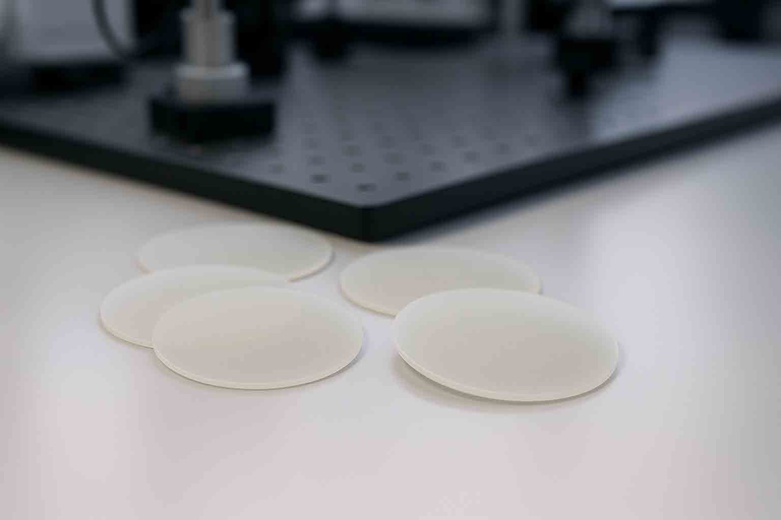 Realistic MgO wafers on a lab surface used as substrates for thin film, photonics, and terahertz research.