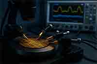 Semiconductor wafer under test with precision probe station and oscilloscope in a research lab environment